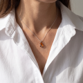 Woman wearing the Darcie Baltic Honey Amber Pendant in Sterling Silver, showcasing genuine honey Baltic amber and polished 925 sterling silver in an elegant luxury jewelry lifestyle setting.