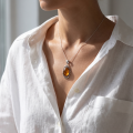 Woman wearing the Evening Baltic Honey Amber Pendant in Sterling Silver, showcasing genuine honey Baltic amber and polished 925 sterling silver in an elegant luxury jewelry lifestyle setting.