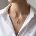 Woman wearing the Serenity Baltic Honey Amber Pendant in Sterling Silver, showcasing genuine honey Baltic amber and polished 925 sterling silver in an elegant luxury jewelry lifestyle setting.