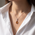 Woman wearing the Fawn Baltic Honey Amber Pendant in Sterling Silver, showcasing genuine honey Baltic amber and polished 925 sterling silver in an elegant luxury jewelry lifestyle setting.