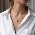 Woman wearing the Vivian Baltic Honey Amber Pendant in Sterling Silver, showcasing genuine honey Baltic amber and polished 925 sterling silver in an elegant luxury jewelry lifestyle setting.