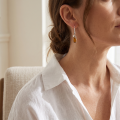 Woman wearing the Gemma Baltic Honey Amber Oval Drop Earrings in Sterling Silver, showcasing genuine honey Baltic amber and polished 925 sterling silver in an elegant luxury jewelry lifestyle setting.