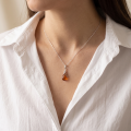 Woman wearing the Eleanor Baltic Amber Pendant in Sterling Silver, showcasing genuine Baltic amber and polished 925 sterling silver in an elegant luxury jewelry lifestyle setting.