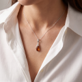 Woman wearing the Summer Baltic Amber Pendant in Sterling Silver, showcasing genuine Baltic amber and polished 925 sterling silver in an elegant luxury jewelry lifestyle setting.