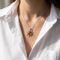 Woman wearing the Flaming Sun Baltic Amber Pendant in Sterling Silver, showcasing genuine Baltic amber and polished 925 sterling silver in an elegant luxury jewelry lifestyle setting.