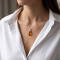 Woman wearing the Bloom Baltic Honey Amber Pendant in Sterling Silver, showcasing genuine honey Baltic amber and polished 925 sterling silver in an elegant luxury jewelry lifestyle setting.