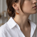 Woman wearing the Clover Baltic Honey Amber Earrings in Sterling Silver, showcasing genuine honey Baltic amber and polished 925 sterling silver in an elegant luxury jewelry lifestyle setting.