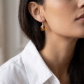 Woman wearing the Baltic Honey Amber Fern Drop Earrings in Sterling Silver, showcasing genuine honey Baltic amber and polished 925 sterling silver in an elegant luxury jewelry lifestyle setting.