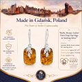 Woman wearing the Baltic Honey Amber Fern Drop Earrings in Sterling Silver, showcasing genuine honey Baltic amber and polished 925 sterling silver in an elegant luxury jewelry lifestyle setting.