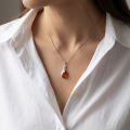 Woman wearing the Maryann Baltic Honey Amber Pendant in Sterling Silver, showcasing genuine honey Baltic amber and polished 925 sterling silver in an elegant luxury jewelry lifestyle setting.