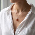 Woman wearing the Serena Baltic Honey Amber Pendant in Sterling Silver, showcasing genuine honey Baltic amber and polished 925 sterling silver in an elegant luxury jewelry lifestyle setting.