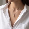Woman wearing the Eliana Baltic Honey Amber Pendant in Sterling Silver, showcasing genuine honey Baltic amber and polished 925 sterling silver in an elegant luxury jewelry lifestyle setting.