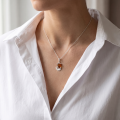 Woman wearing the Sailboat Baltic Honey Amber Pendant in Sterling Silver, showcasing genuine honey Baltic amber and polished 925 sterling silver in an elegant luxury jewelry lifestyle setting.