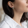 Woman wearing the Baltic Green Amber Stud Earrings in Sterling Silver, showcasing genuine green Baltic amber and polished 925 sterling silver in an elegant luxury jewelry lifestyle setting.