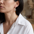 Woman wearing the Roses Baltic Honey Amber Drop Earrings in Sterling Silver, showcasing genuine honey Baltic amber and polished 925 sterling silver in an elegant luxury jewelry lifestyle setting.