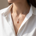 Woman wearing the Agnella Baltic Amber Pendant in Sterling Silver, showcasing genuine Baltic amber and polished 925 sterling silver in an elegant luxury jewelry lifestyle setting.