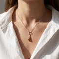 Woman wearing the Triangle Baltic Honey Amber Pendant in Sterling Silver, showcasing genuine honey Baltic amber and polished 925 sterling silver in an elegant luxury jewelry lifestyle setting.