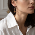 Woman wearing the Michelle Baltic Honey Amber Drop Earrings in Sterling Silver, showcasing genuine honey Baltic amber and polished 925 sterling silver in an elegant luxury jewelry lifestyle setting.