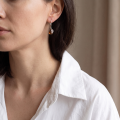 Woman wearing the Aniela Baltic Honey Amber Drop Earrings in Sterling Silver, showcasing genuine honey Baltic amber and polished 925 sterling silver in an elegant luxury jewelry lifestyle setting.