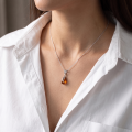 Woman wearing the Aniela Baltic Honey Amber Pendant in Sterling Silver, showcasing genuine honey Baltic amber and polished 925 sterling silver in an elegant luxury jewelry lifestyle setting.