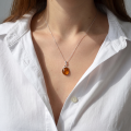Woman wearing the Baltic Honey Amber Pendant Necklace in Sterling Silver, showcasing genuine honey Baltic amber and polished 925 sterling silver in an elegant luxury jewelry lifestyle setting.