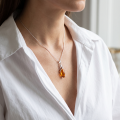Woman wearing the Baltic Amber Pendant in Sterling Silver, showcasing genuine Baltic amber and polished 925 sterling silver in an elegant luxury jewelry lifestyle setting.