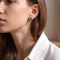 Woman wearing the Baltic Honey Amber Oval Stud Earrings in Sterling Silver, showcasing genuine honey Baltic amber and polished 925 sterling silver in an elegant luxury jewelry lifestyle setting.