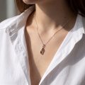 Woman wearing the Baltic Honey Amber Pendant in Sterling Silver, showcasing genuine honey Baltic amber and polished 925 sterling silver in an elegant luxury jewelry lifestyle setting.