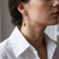 Woman wearing the Angela Baltic Honey Amber Drop Earrings in Sterling Silver, showcasing genuine honey Baltic amber and polished 925 sterling silver in an elegant luxury jewelry lifestyle setting.