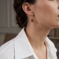 Woman wearing the Mia Baltic Honey Amber Earrings in Sterling Silver, showcasing genuine honey Baltic amber and polished 925 sterling silver in an elegant luxury jewelry lifestyle setting.