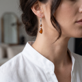 Woman wearing the Baltic Honey Amber Drop Earrings in Sterling Silver, showcasing genuine honey Baltic amber and polished 925 sterling silver in an elegant luxury jewelry lifestyle setting.