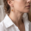 Woman wearing the Baltic Honey Amber Drop Earrings in Sterling Silver, showcasing genuine honey Baltic amber and polished 925 sterling silver in an elegant luxury jewelry lifestyle setting.