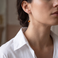 Woman wearing the Baltic Honey Amber Drop Earrings in Sterling Silver, showcasing genuine honey Baltic amber and polished 925 sterling silver in an elegant luxury jewelry lifestyle setting.