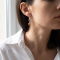 Woman wearing the Sanchia Baltic Honey Amber Drop Earrings in Sterling Silver, showcasing genuine honey Baltic amber and polished 925 sterling silver in an elegant luxury jewelry lifestyle setting.