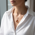Woman wearing the Emma Baltic Honey Amber Oval Pendant in Sterling Silver, showcasing genuine honey Baltic amber and polished 925 sterling silver in an elegant luxury jewelry lifestyle setting.
