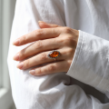 Woman wearing the Devee Baltic Honey Amber Ring in Sterling Silver, showcasing genuine honey Baltic amber and polished 925 sterling silver in an elegant luxury jewelry lifestyle setting.