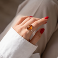 Woman wearing the Baltic Honey Amber Oval Adjustable Ring in Sterling Silver, showcasing genuine honey Baltic amber and polished 925 sterling silver in an elegant luxury jewelry lifestyle setting.