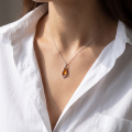 Woman wearing the Baltic Honey Amber Pendant in Sterling Silver, showcasing genuine honey Baltic amber and polished 925 sterling silver in an elegant luxury jewelry lifestyle setting.