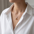 Woman wearing the Baltic Honey Amber Pear-Shaped Pendant in Sterling Silver, showcasing genuine pear-shaped honey Baltic amber and polished 925 sterling silver in an elegant luxury jewelry lifestyle setting.