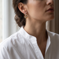 Woman wearing the Aileen Baltic Amber Stud Earrings in Sterling Silver, showcasing genuine Baltic amber gemstones and polished 925 sterling silver in an elegant luxury jewelry lifestyle setting.