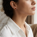 Woman wearing the Hearts Baltic Honey Amber Stud Earrings in Sterling Silver, showcasing genuine honey Baltic amber gemstones and polished 925 sterling silver in an elegant luxury jewelry lifestyle setting.