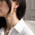 Woman wearing the Stephanie Baltic Honey Amber Drop Earrings in Sterling Silver, showcasing genuine honey Baltic amber gemstones and polished 925 sterling silver in an elegant luxury jewelry lifestyle setting.