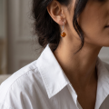 Woman wearing the Baltic Honey Amber Round Drop Earrings in Sterling Silver, showcasing genuine round honey Baltic amber gemstones and polished 925 sterling silver in an elegant luxury jewelry lifestyle setting.
