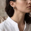 Woman wearing the Ruth Baltic Honey Amber Stud Earrings in Sterling Silver, showcasing genuine honey Baltic amber gemstones and polished 925 sterling silver in an elegant luxury jewelry lifestyle setting.