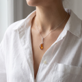Woman wearing the Milena Baltic Honey Amber Pendant in Sterling Silver, showcasing genuine honey Baltic amber and polished 925 sterling silver in an elegant luxury jewelry lifestyle setting.