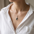 Close-up of a model wearing the “Freya” Baltic Green Amber Pendant in Sterling Silver.