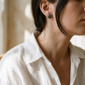 “Anika” Baltic Green Amber Stud Earrings in Sterling Silver worn on a model, shown in a close-up side view.